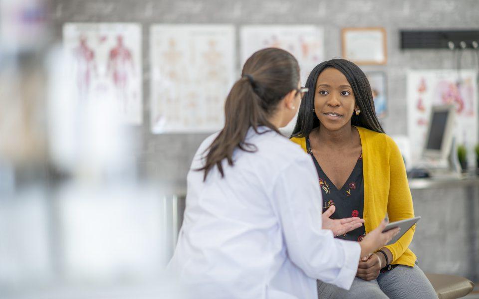 A young doctor shares her tablet with the patient. The patient smiles as she looks at the doctor.